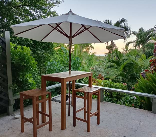 Private terrace seating beneath an umbrella overlooking Muri Retreat's tropical gardens